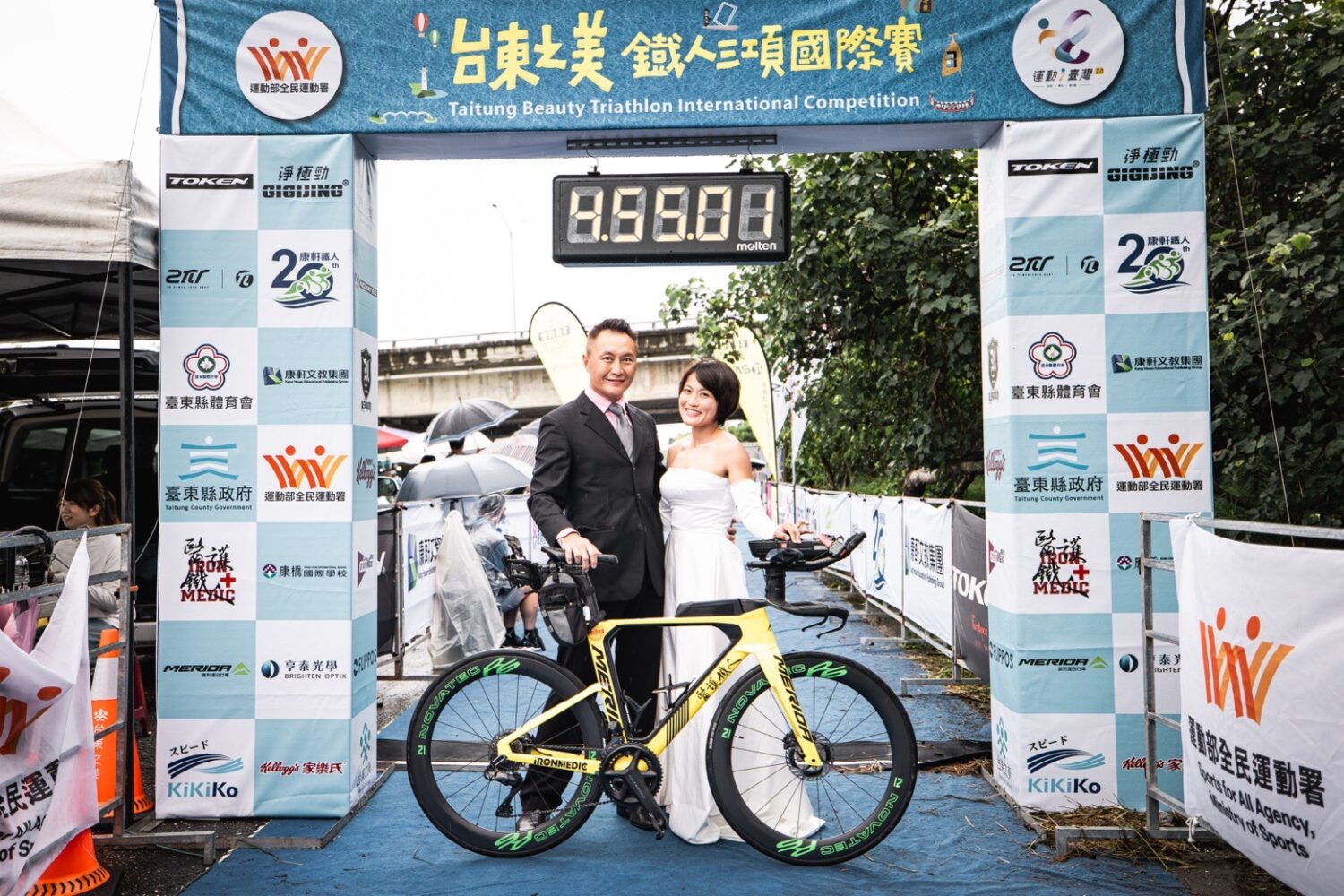 陳彥良（左）與洪緯欣（右）身穿西裝與白紗於終點拱門前合影，象徵鐵人終點即是愛情起點。（圖/記者張家燁翻攝）