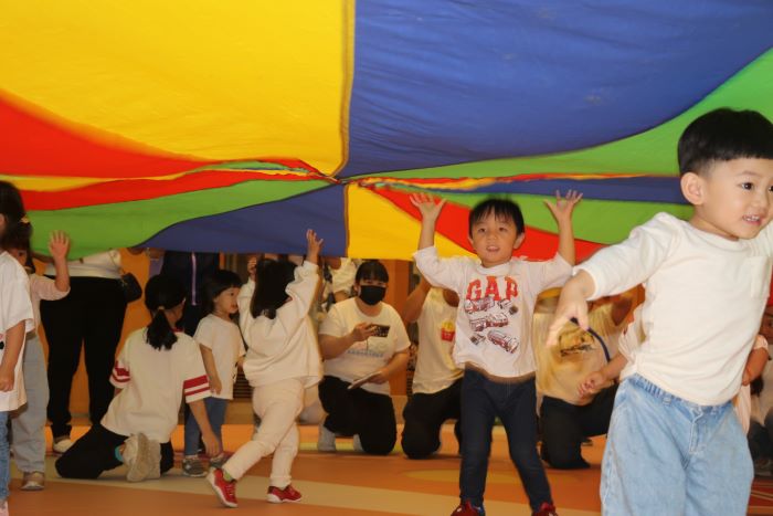 《圖說》小朋友躲在氣球傘下玩。〈社會局提供〉